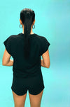 Person wearing a black t-shirt and shorts against a light blue background