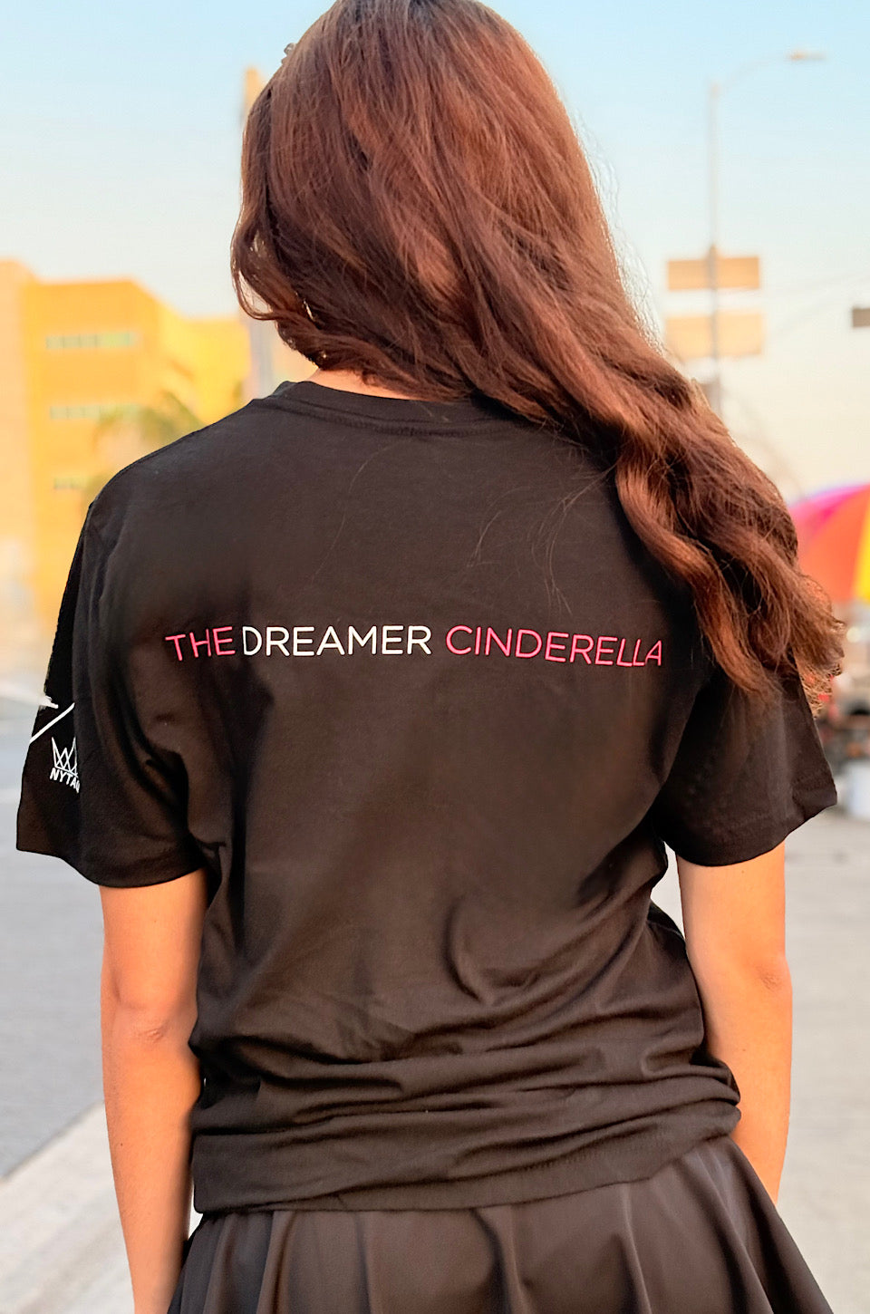 Woman wearing a black t-shirt with a colorful graphic design on a street.